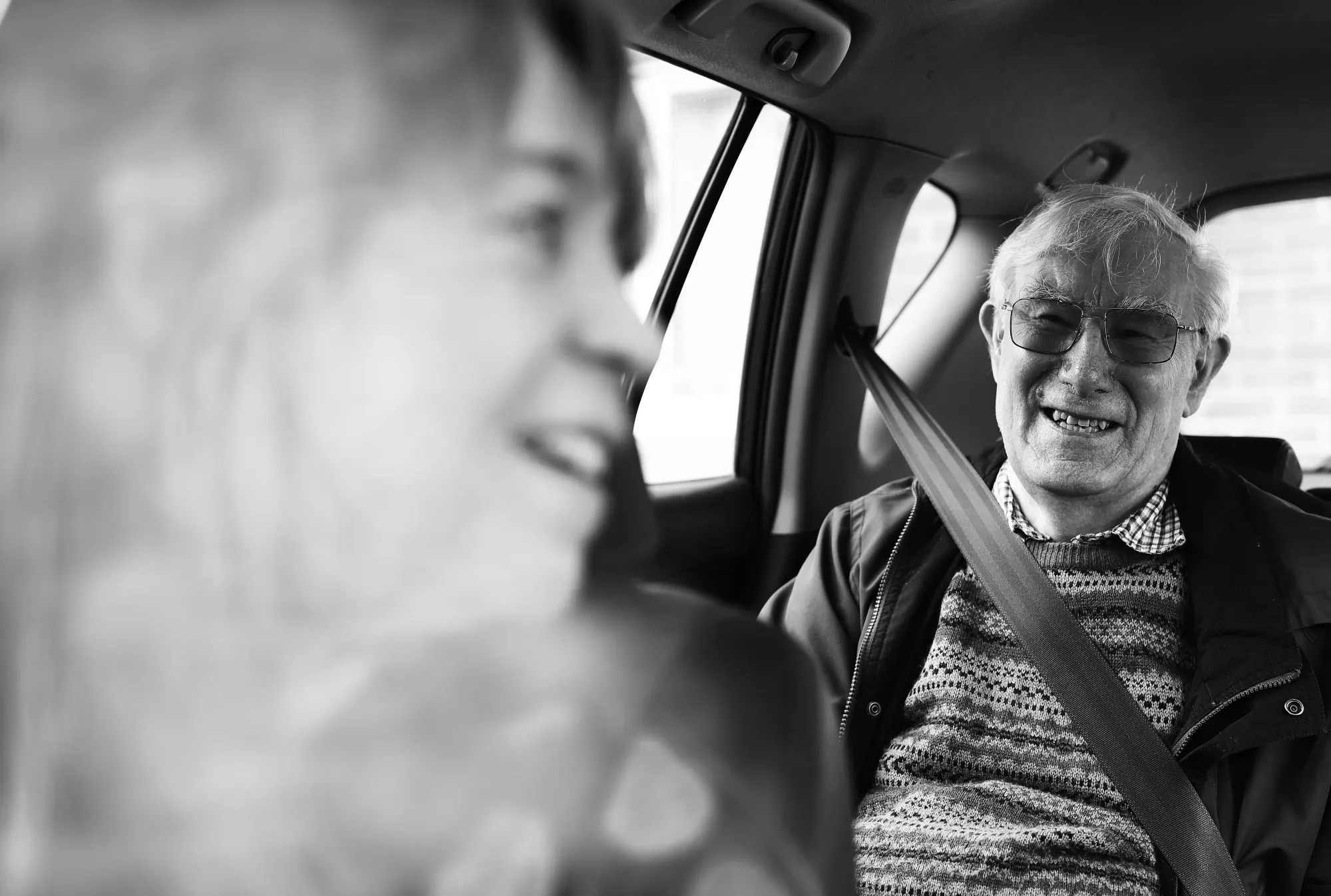 A passenger in the back of a car, smiling at the volunteer driver.